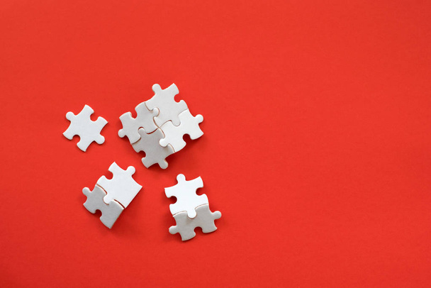 White details of puzzle on red background. - Фото, изображение