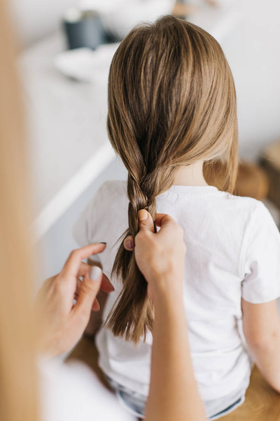 Mother braids her daughter's hair - Foto, Bild