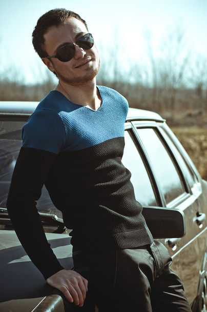 Beautiful man with car in fashionable clothes. Fashion portrait - Фото, зображення