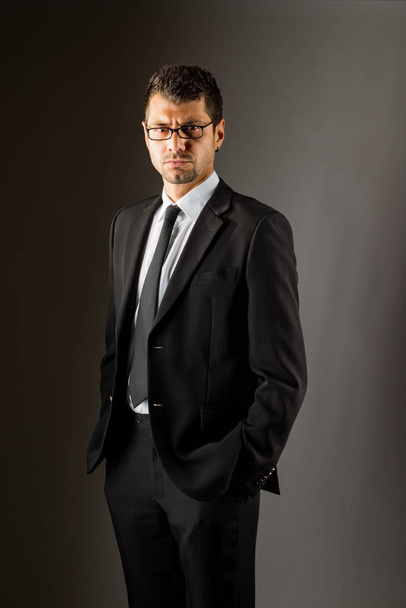 A serious man in a black suit. dark background. - Photo, Image