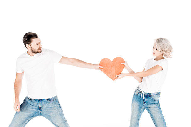 Young adult couple pulling one red big heart shape to each other isolated on white - Φωτογραφία, εικόνα