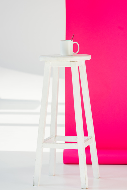 branco pintado cadeira de madeira com copo e papel de parede rosa no fundo
 - Foto, Imagem