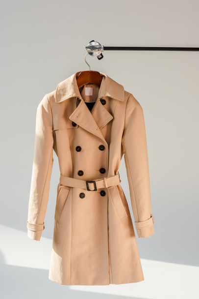 beige trench coat with belt and black buttons on hanger - Photo, Image