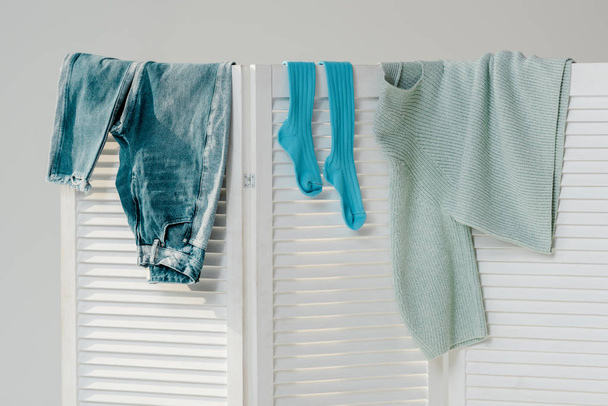 close up of blue clothes hanging on white room divider isolated on grey - Foto, imagen