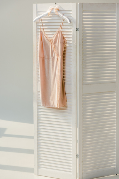 silk nightie with lace hanging on white room divider  - Photo, Image
