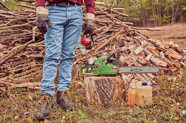 Dřevorubec s pilou a hromadu řezu dřevin. - Fotografie, Obrázek