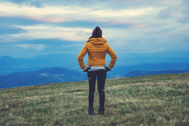 Mujer de pie en un prado de montaña vacío
. - Foto, imagen