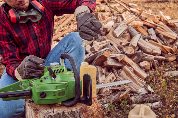 Lumberjack with chainsaw and pile of cut woods. - Photo, Image