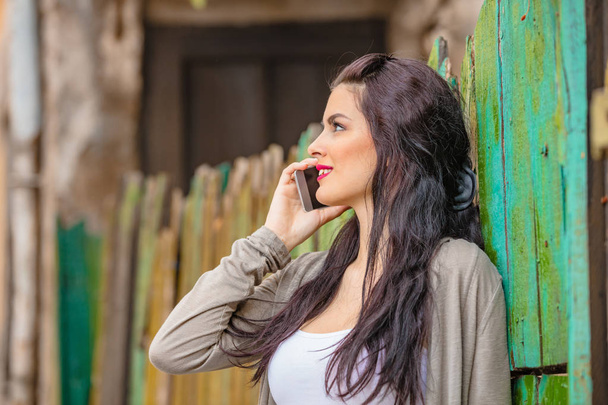 Söpö nuori nainen käyttää matkapuhelinta kaupunkiympäristössä
. - Valokuva, kuva