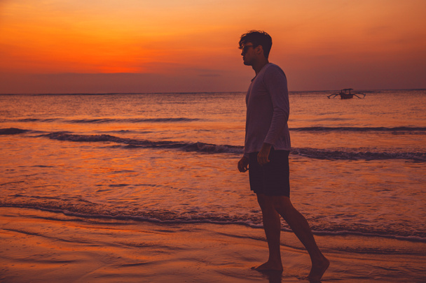 Чоловік насолоджується океанським пляжем під час заходу сонця / заходу сонця
. - Фото, зображення