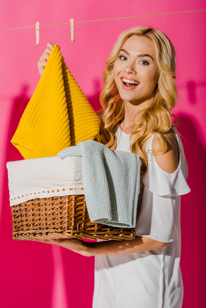 close up of happy woman getting out clothes from wicker basket  - Photo, Image