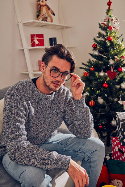 Hombre sentado en un sofá y esperando solo para Navidad / Nochevieja
. - Foto, imagen