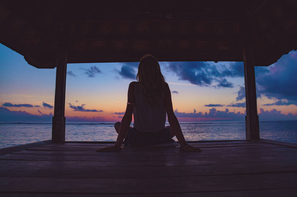 Silhouette di una ragazza che si gode l'alba / tramonto su una pagoda oceanica
. - Foto, immagini