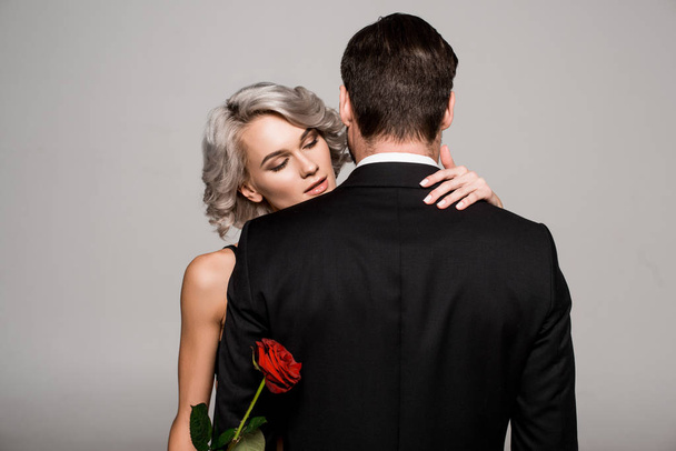 Couple of young adult hugging while woman holding red rose - Foto, Imagem