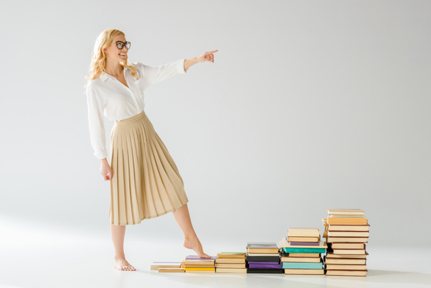 mujer feliz en gafas caminando sobre escalones hechos de libros
   - Foto, imagen