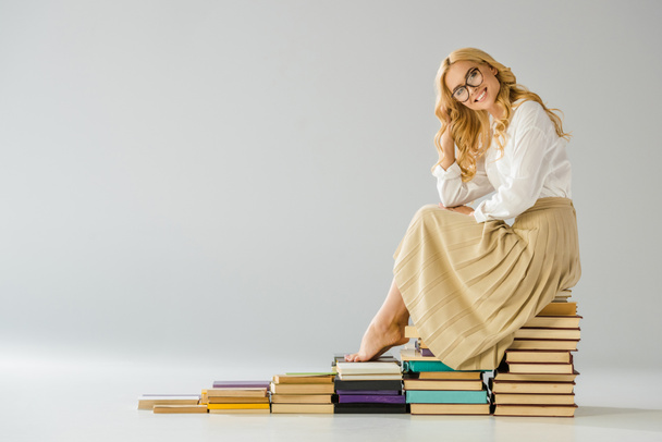 Szczęśliwa kobieta boso w okularach siedzący na schodach z książek   - Zdjęcie, obraz