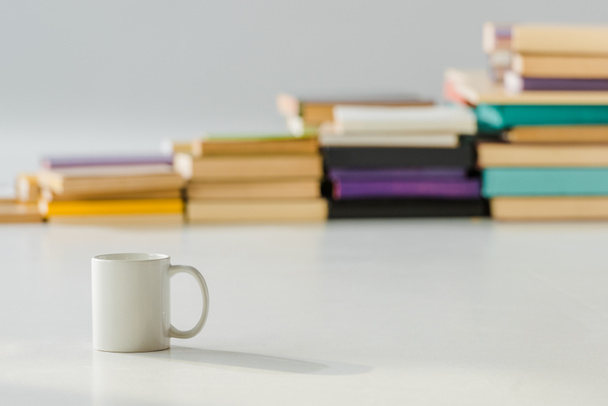 close up of white cup with aged pile of books on background - 写真・画像