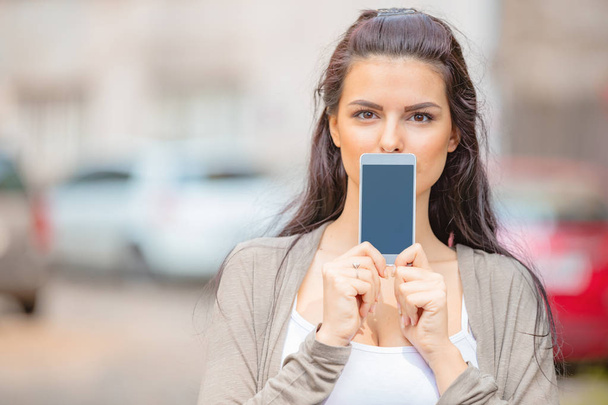 Милая молодая женщина, использующая мобильный телефон в городской среде
. - Фото, изображение