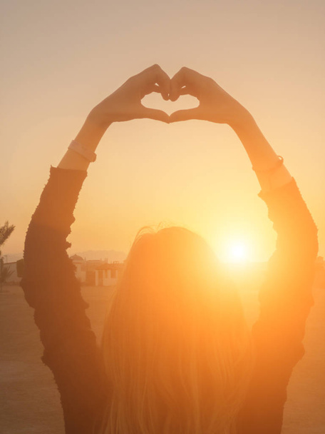 Dziewczyna trzyma kształt serca w zachód Słońca / Wschód słońca czas. - Zdjęcie, obraz