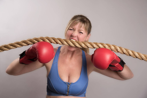 Muotokuva riemukkaasta naisnyrkkeilijästä punaisissa nyrkkeilyhanskoissa
 - Valokuva, kuva