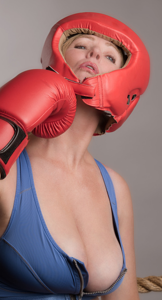 Vrouwelijke bokser dragen een hoofd veiligheidsdeur en het nemen van een punch - Foto, afbeelding