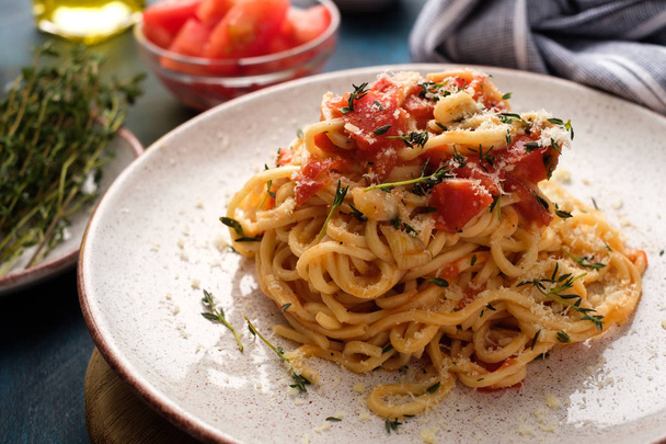 スパゲッティバジルとトマトと青いテーブルの上の皿でタイム. - 写真・画像