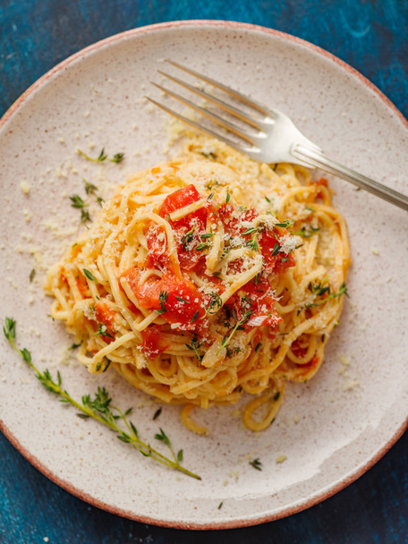 Spaghettis aux tomates et thym dans une assiette sur une table bleue. Vue du dessus
. - Photo, image