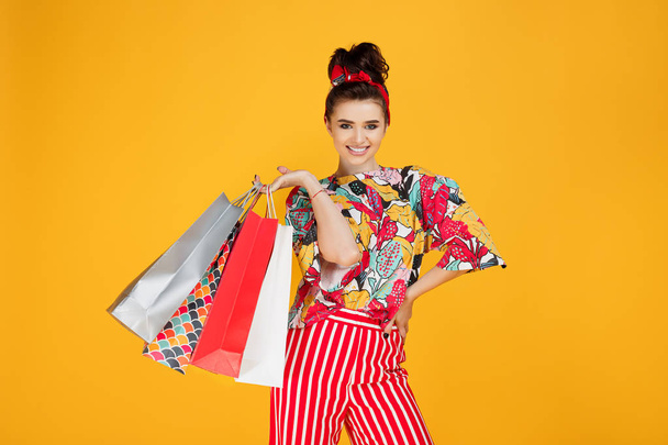 Young happy caucasian woman in casual colorful clothes holding bags and shopping over orange background. - Valokuva, kuva