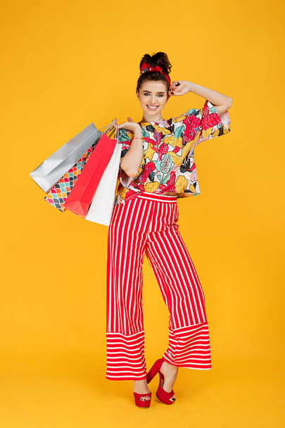 Full lenhts photo of young happy caucasian woman in casual colorful clothes holding bags and shopping over orange background. - Fotoğraf, Görsel