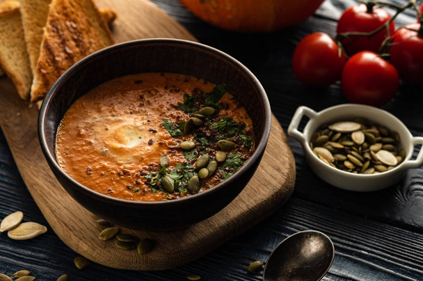 Pumpkin soup with sour cream and pumpkin seeds on a wooden table - Photo, Image