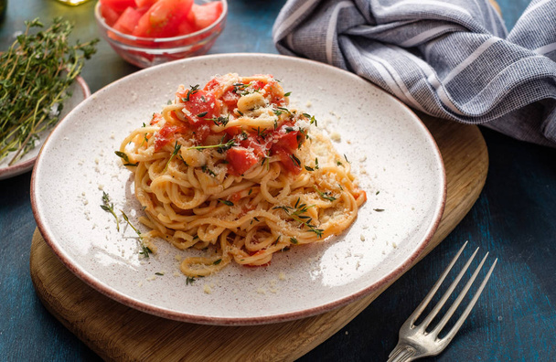 Μακαρόνια με ντομάτα και θυμάρι σε ένα πιάτο στο τραπέζι μπλε. - Φωτογραφία, εικόνα