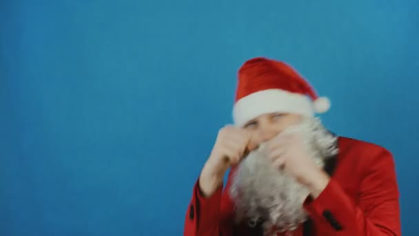 Christmas and New year, man like a Santa is boxing and throws punches by his fists at the camera, on blue background - Video
