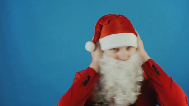 Christmas, man like a Santa covers his ears by palms of hands, New year 2019, blue background - Πλάνα, βίντεο