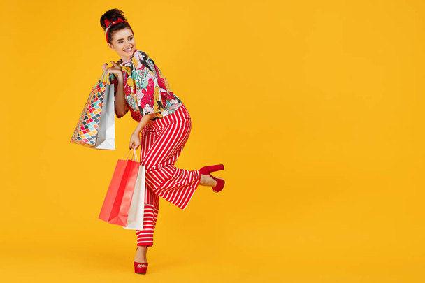 Full lenhts photo of young happy caucasian woman in casual colorful clothes holding bags and shopping over orange background. - Foto, imagen