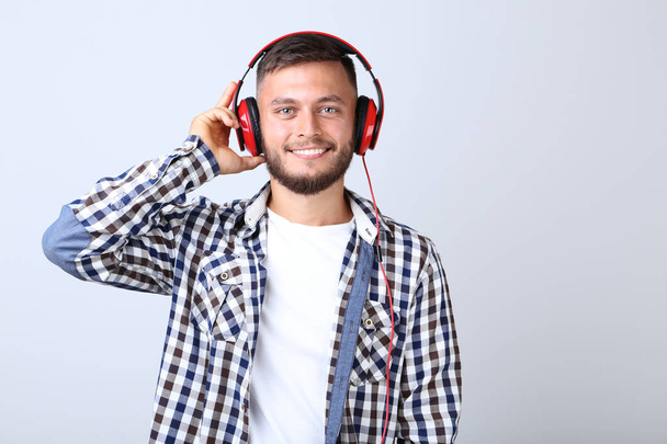 Young man with red headphones on grey background - Foto, imagen