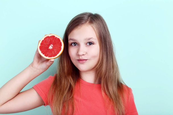 Cute young girl with grapefruit on mint background - Foto, Imagem