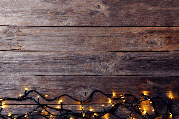 Χριστουγεννιάτικη γιρλάντα ανάβει γκρι ξύλινο τραπέζι - Φωτογραφία, εικόνα
