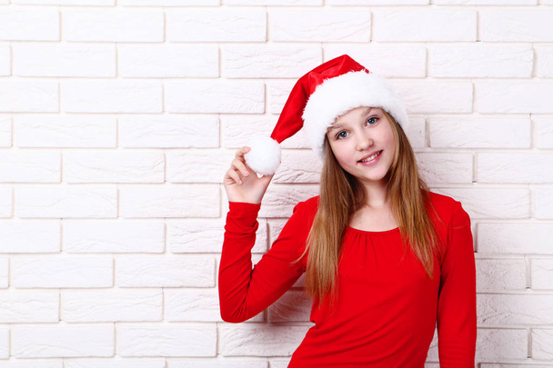 Young girl in santa hat on brick wall background - Foto, imagen