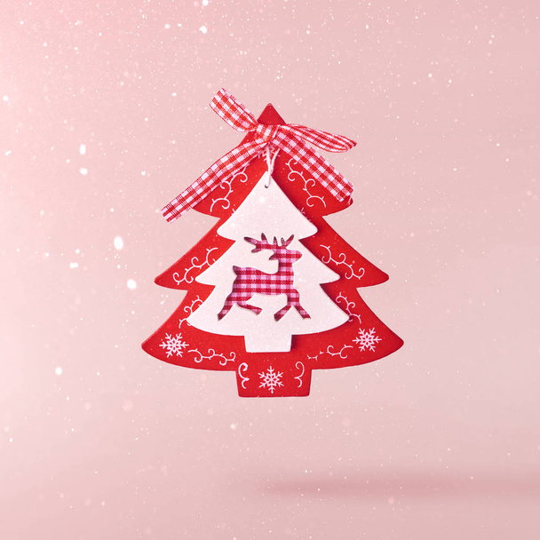Χριστουγεννιάτικη ιδέα. Δημιουργική σύλληψη Χριστουγέννων πραγματοποίησε πέφτουν με αέρα χριστουγεννιάτικο δέντρο διακόσμηση ροζ φόντο. Ελάχιστη έννοια - Φωτογραφία, εικόνα