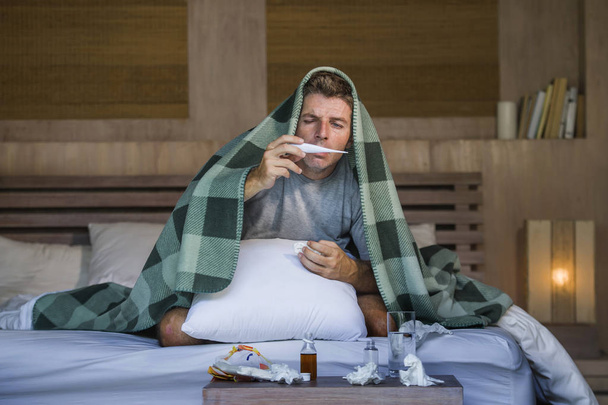 young sick wasted and exhausted man at home bed lying feeling unwell suffering cold and flu sneezing nose with tissues having virus and headache in domestic health care and grippe concept - Photo, image