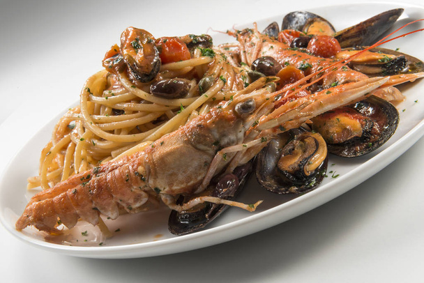 Тарелка спагетти с креветками оливки и помидоры на белом фоне
 - Фото, изображение