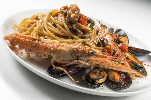 Тарілка спагеті з креветками мідіями оливками та помідорами на білому тлі
 - Фото, зображення