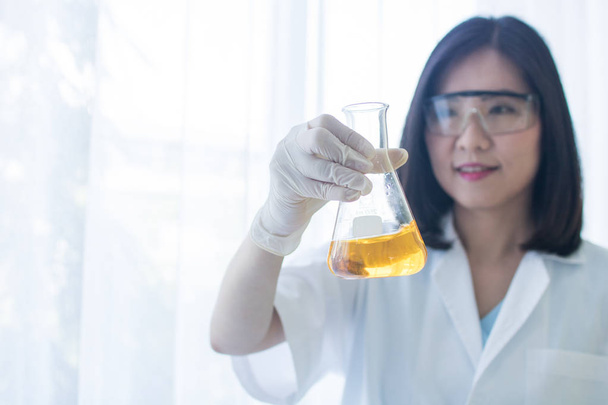 wetenschapper vrouw Holding test glas in Lab, jonge onderzoeker testen chemische reagens in laboratorium  - Foto, afbeelding