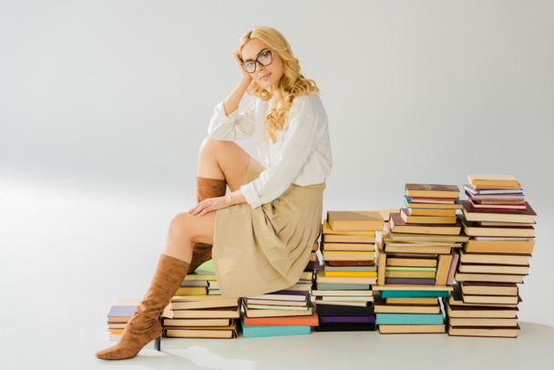 schöne blonde Frau mit Brille sitzt auf einem Stapel Retro-Bücher - Foto, Bild