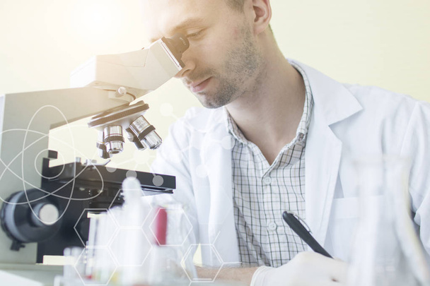 Genç adam bilim adamı veya laboratuarda araştırmacı araştırma ve mikroskop bakıyor  - Fotoğraf, Görsel