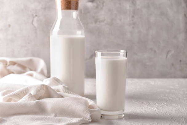 Copo e garrafa de leite saboroso na mesa branca
 - Foto, Imagem