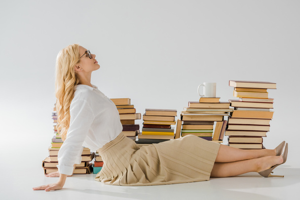 красивая женщина, сидящая на полу возле стопки книг
  - Фото, изображение