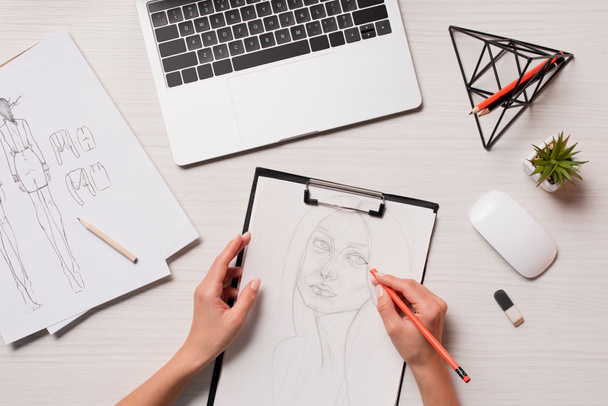 офисный стол с ноутбуком, художественными принадлежностями и обрезанным видом дизайнера, работающего над эскизами, плоский уголок
 - Фото, изображение