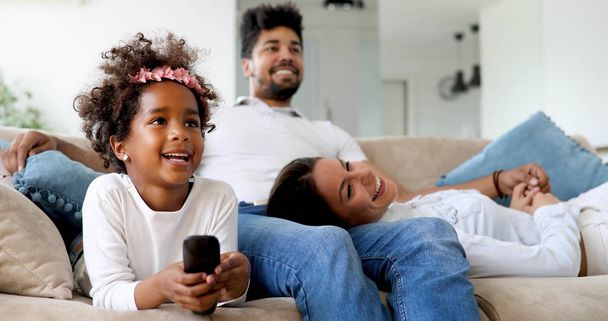 Young cute girl watching tv with her parents - Фото, изображение