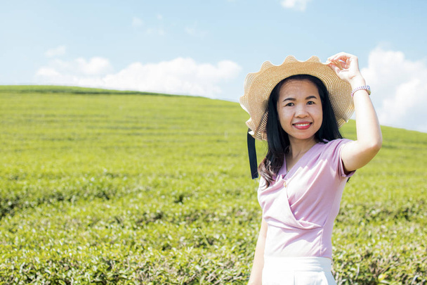 retrato de la hermosa mujer tailandesa con sombrero y la publicación en el té verde archivado con el cielo azul
 - Foto, Imagen
